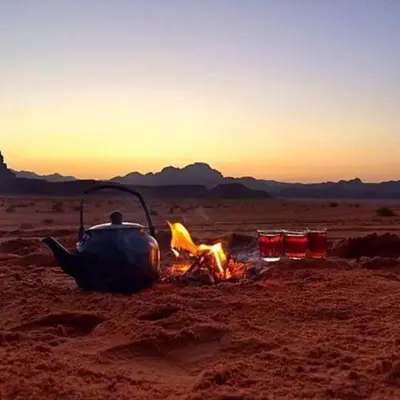 a teapot sitting over a camp fire in the desert at Wadi Rum Lawrence Camp in Wadi Rum