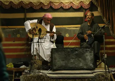 a man playing a guitar and a man playing a instrument at Captains Desert Camp in Wadi Rum