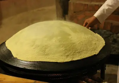 a person is making a dough on a pan at Captains Desert Camp in Wadi Rum