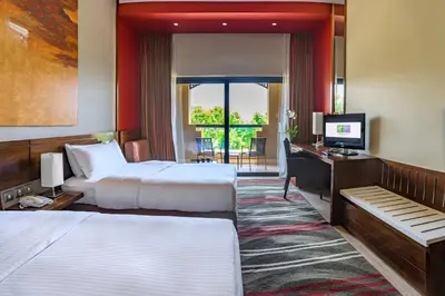 a hotel room with two beds and a desk and a television at Holiday Inn Resort Dead Sea by IHG in Sowayma