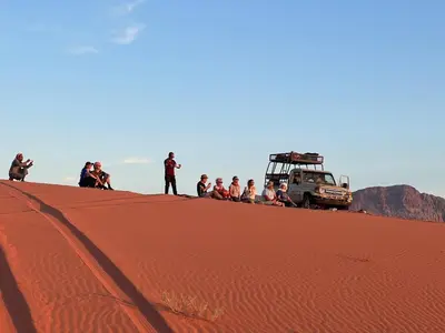 a group of people standing on top of a sand dune at Wadi Rum Desert Camp in Wadi Rum