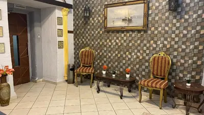 two chairs and a table and a painting on a wall at New Park Hotel in Amman