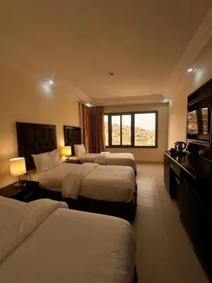 a hotel room with three beds and a window at Sharah Mountains Hotel in Wadi Musa
