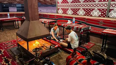 two men are cooking over a fire in an auditorium at Beauty Wadi Rum Luxury Camp in Wadi Rum