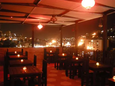 a restaurant with tables and candles on the roof at night at Arab Tower Hotel in Amman