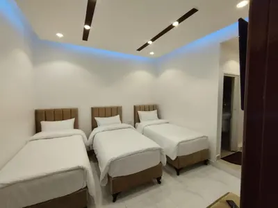 three beds in a room with white walls at Mussa Spring Hotel in Wadi Musa