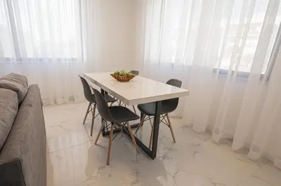 a white table and chairs in a room with curtains at Al Kawther Hotel Apartments in Amman