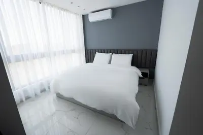 a bedroom with a white bed and a window at Al Kawther Hotel Apartments in Amman