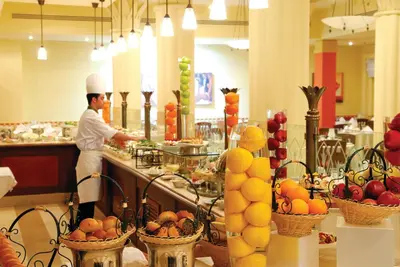 a chef standing in a kitchen preparing food at Marina Plaza Hotel, Tala Bay in Aqaba