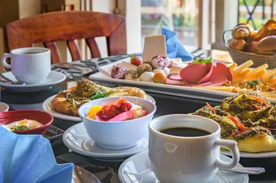 a table with plates of food and a cup of coffee at Marina Plaza Hotel, Tala Bay in Aqaba