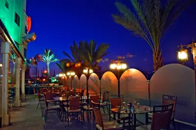 a restaurant with tables and chairs at night at Larsa Hotel in Amman