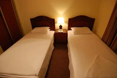 two beds in a small room with a lamp on a night stand at Al Rashid Hotel in Wadi Musa