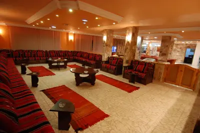 a large waiting room with red chairs and tables at Al Rashid Hotel in Wadi Musa