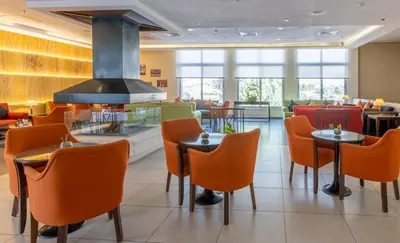a restaurant with orange chairs and tables and a fireplace at Petra Guest House Hotel in Petra