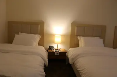 two beds in a hotel room with a lamp between them at Silk Road Hotel in Wadi Musa