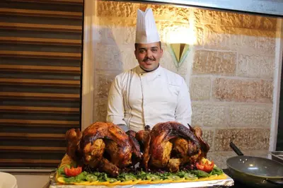 a chef standing next to a turkey on a platter at Edom Hotel in Wadi Musa