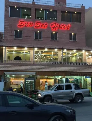 a truck parked in front of a building with a neon sign at Sunset Hotel in Wadi Musa