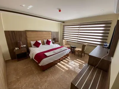 a bedroom with a bed and a table and a desk at Sunset Hotel in Wadi Musa