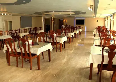 a dining room with white tables and wooden chairs at Al Raad Hotel in Aqaba