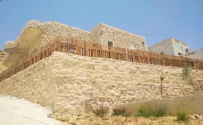 a stone wall with a fence on top of it at The Little B&B on the Hill in Wadi Musa