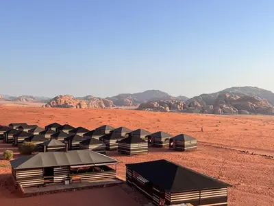 a row of tents in a desert with mountains at Wadi Rum Bedouin Way Camp in Wadi Rum