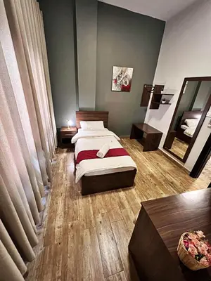 a bedroom with two beds and a mirror at The Sydney Hotel in Amman