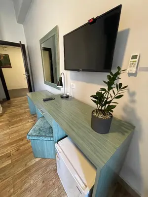 a desk with a flat screen tv on a wall at The Sydney Hotel in Amman