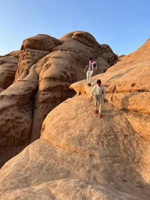 two people walking on top of some rocks at Bedouin Tours Camp in Wadi Rum