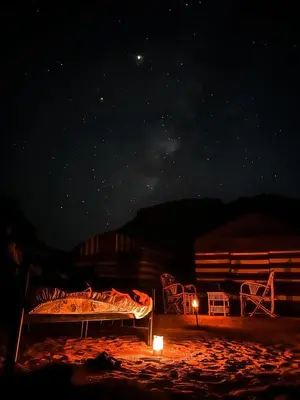 a bed is lit up at night under the stars at Bedouin Tours Camp in Wadi Rum