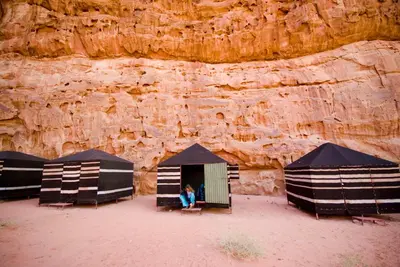 a person sitting in a tent in front of a cliff at Wadi Rum Fire Camp in Wadi Rum