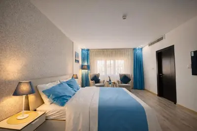 a bedroom with a blue and white bed and blue curtains at Al Basem Hotel in Amman