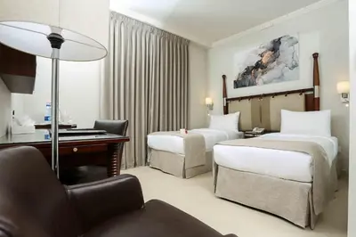 a hotel room with two beds and a desk at Retaj Hotel in Amman