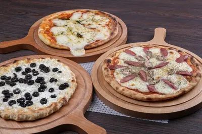 three pizzas sitting on wooden plates on a table at Retaj Hotel in Amman