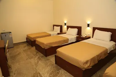 a hotel room with two beds and two tables at Rumman Hotel in Madaba