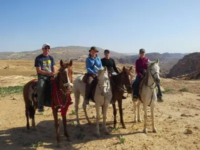 a group of people riding horses in the desert at Happy Bedouin House Petra in Al Ḩayy