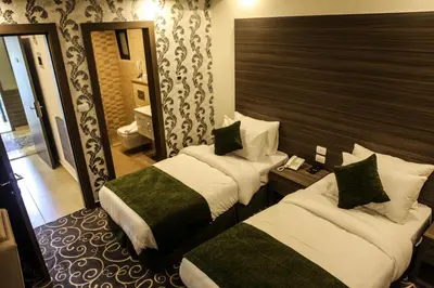 a hotel room with two beds and a mirror at Almond Hotel Apartments in Amman