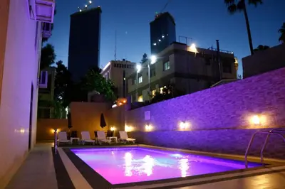 a swimming pool with purple lighting in a city at night at Almond Hotel Apartments in Amman