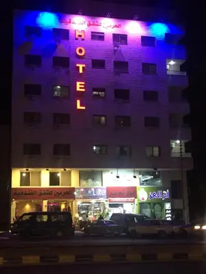 a hotel with a neon sign on the side of it at Al haramain Furnished Apartments in Amman