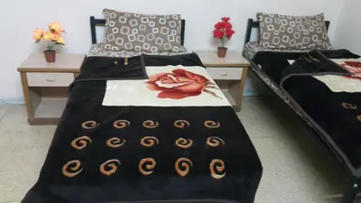 two beds in a room with two tables at Cliff Hostel in Amman