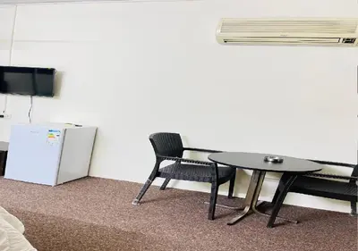 a room with a table and two chairs and a refrigerator at Asia Hotel in Amman