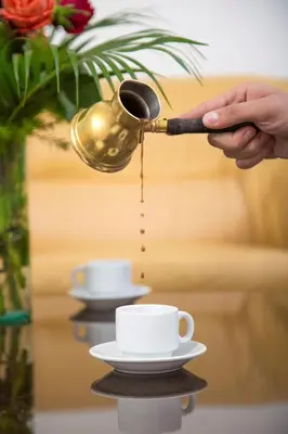 a person pouring coffee from a coffee pot into a cup at Barakat Hotel Apartments in Amman