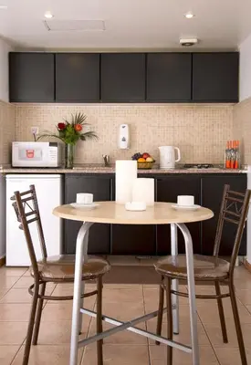 a kitchen with a wooden table and two chairs at Barakat Hotel Apartments in Amman