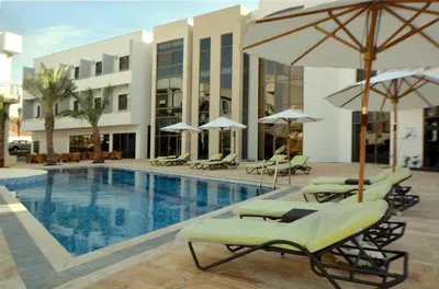a pool with lounge chairs and umbrellas next to a building at Public Security Hotel & Chalets in Aqaba