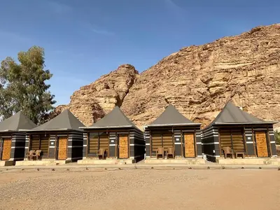a row of wooden buildings in front of a mountain at Hasan Zawaideh Camp in Wadi Rum