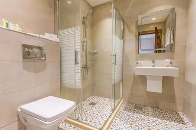 a bathroom with a shower and a toilet and a sink at The Seventh Star Hotel Suites in Amman