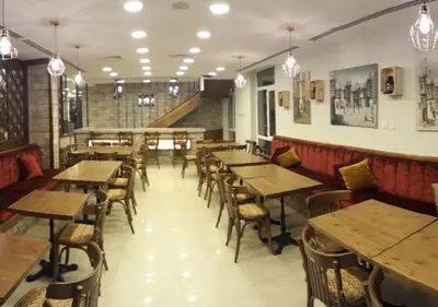 an empty restaurant with wooden tables and chairs at The Seventh Star Hotel Suites in Amman