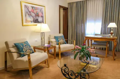 a living room with chairs and a table and a living room at Amman International Hotel in Amman