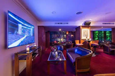 a bar with leather chairs and a large screen at Amman International Hotel in Amman
