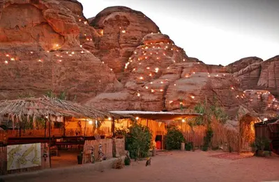 a building with lights in front of a mountain at Seven Wonders Bedouin Camp in Wadi Musa