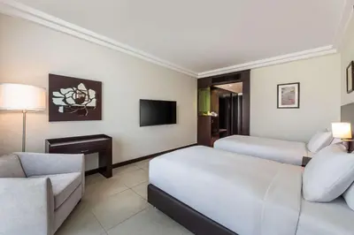 a hotel room with two beds and a couch and a tv at DoubleTree by Hilton Hotel Aqaba in Aqaba